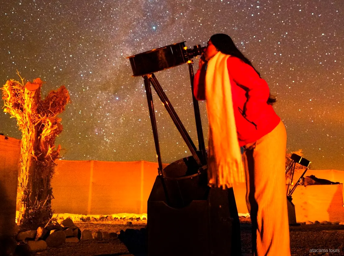 Atacama tours combo, reiziger kijkt door een grote telescoop onder de sterrenhemel van de woestijn