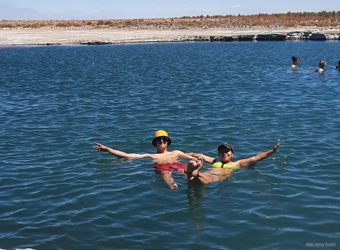 Excursions dans l'Atacama : deux visiteurs flottent bras écartés dans l'eau salée de la Laguna Cejar