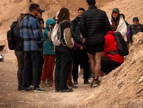 Atacama tours group in warm jackets gathered with their guide on a sandy trail in Moon Valley