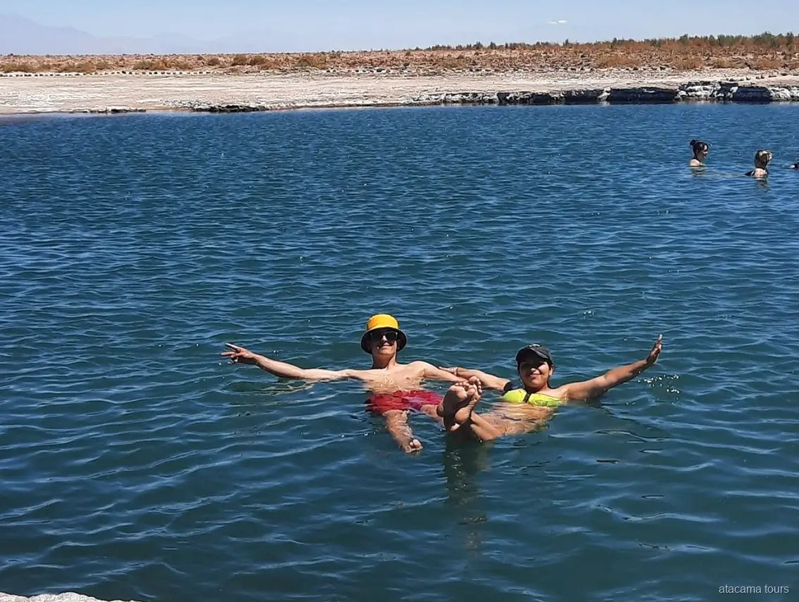 Passeios no Atacama: dois visitantes flutuam de braços abertos na água salgada da Laguna Cejar