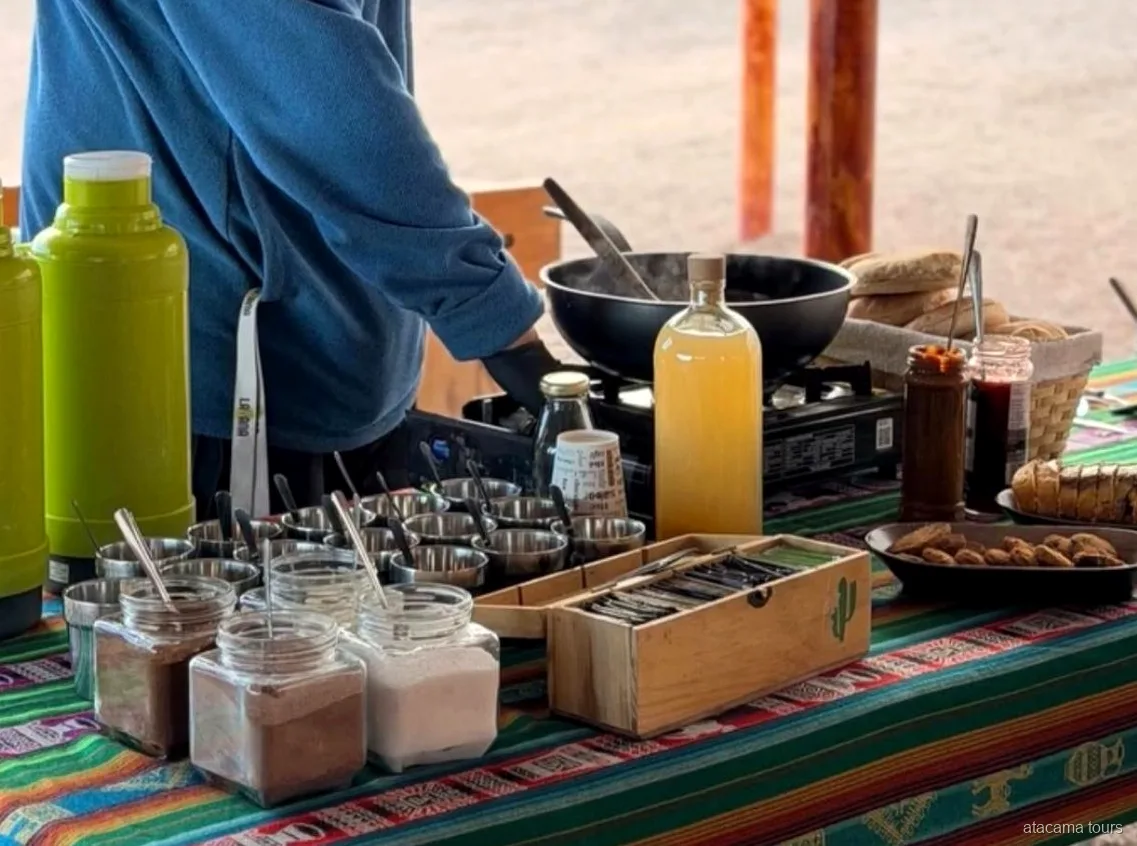 Spuntino dei tour nel deserto di Atacama, thermos, barattoli, pane e fornello su una tovaglia andina a righe