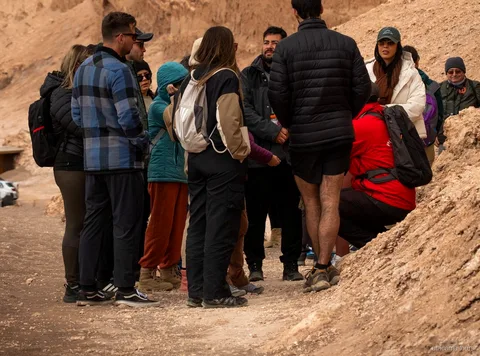 Grupo de tours en Atacama con chaquetas de abrigo reunido junto a su guía en un sendero del Valle de la Luna