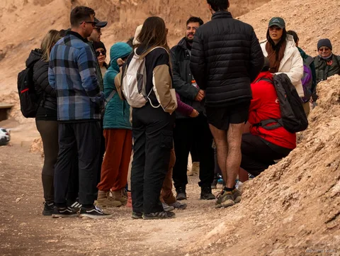 Groep op Atacama tours in warme jassen verzameld rond de gids op een zandpad in de Valle de la Luna